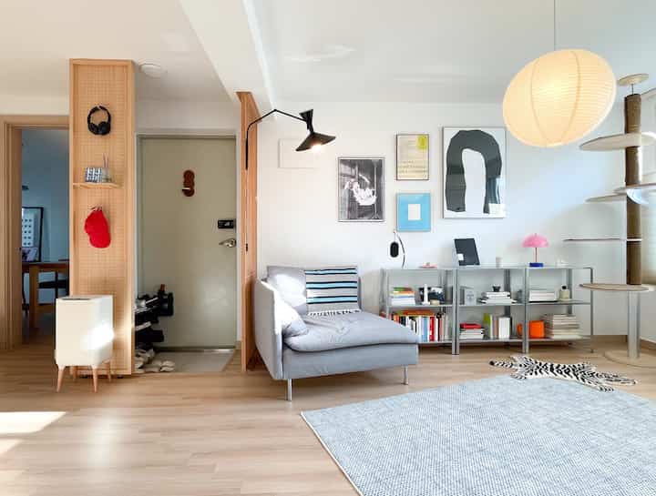 明るい木目調とホワイトトーンのワンルームリビング、ミニマルモダン家具とキャットタワーが配置された雰囲気のあるインテリア