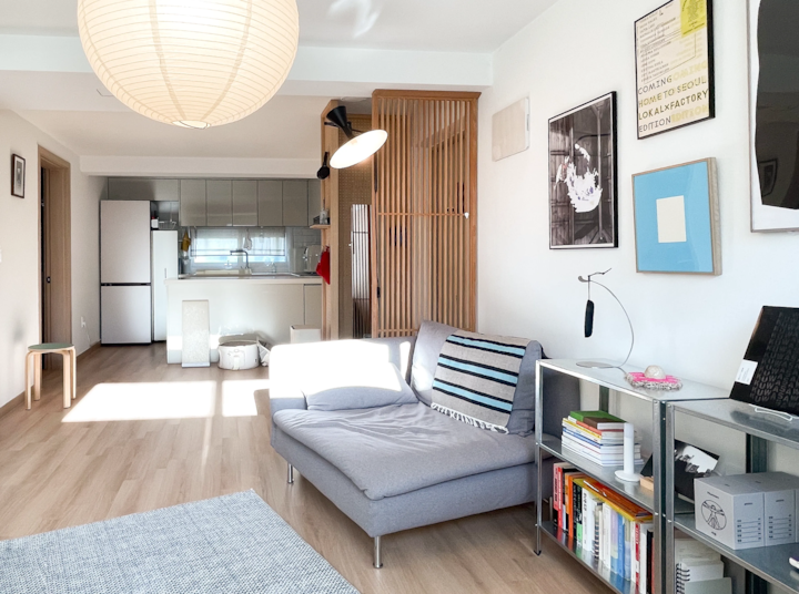 白とナチュラルトーンのワンルーム、居間とキッチンが調和した明るく居心地の良い空間