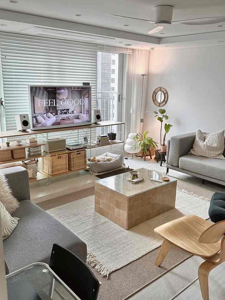 明るくナチュラルな色調のリビング、グレーのソファ2台とベージュのタイルコーヒーテーブル、ペットの猫と植物が配置された居心地の良い空間