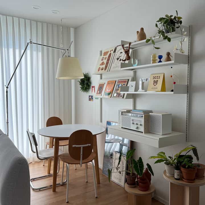 白と茶色のトーンのダイニングルーム、丸テーブルと椅子が配置されたナチュラルモダンな家族空間