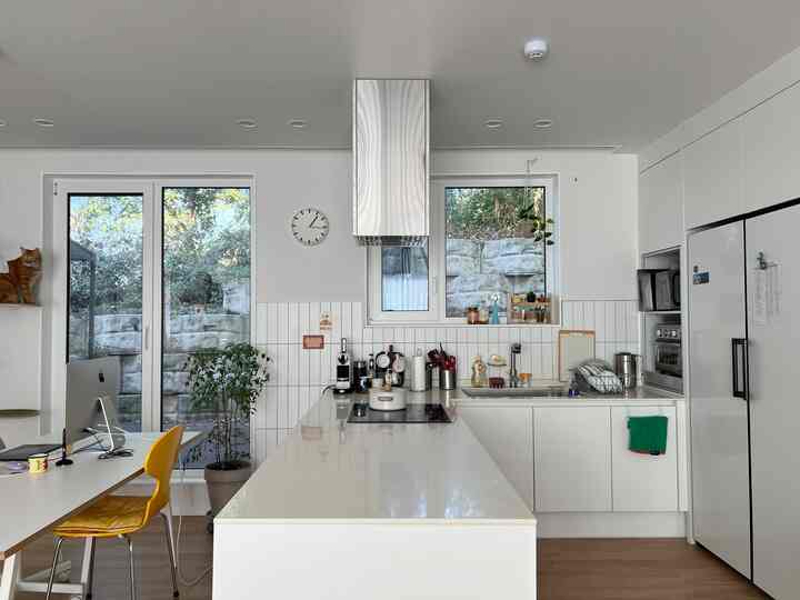 白とナチュラルカラーのキッチン空間、大きな窓とアイランドカウンターが配置された清潔感のある明るいインテリア