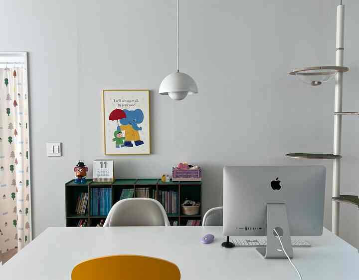 白と緑の色調のホームオフィス、机とコンピューター、本棚が配置された落ち着いた雰囲気のインテリア