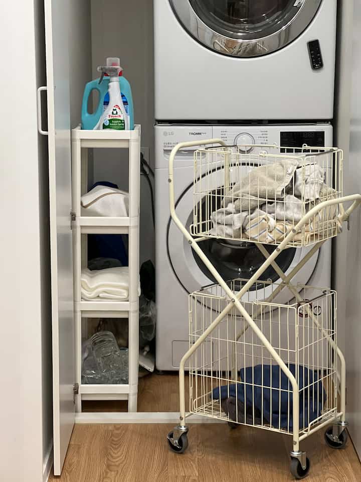 ホワイトとウッドトーンを基調としたランドリールーム、イケアの4段棚と移動式ワイヤーランドリーバスケットが配置された清潔感のあるインテリア