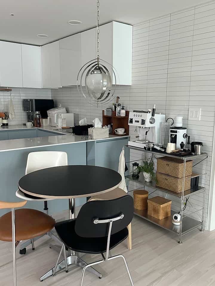 白と黒のトーンのダイニングルーム、丸い黒いテーブルと様々な椅子が配置されたモダンなホームカフェ空間