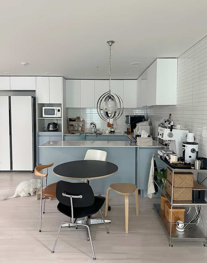 白と木目調のモダンなキッチンとダイニング、コーヒーマシンと猫がいる雰囲気のある空間
