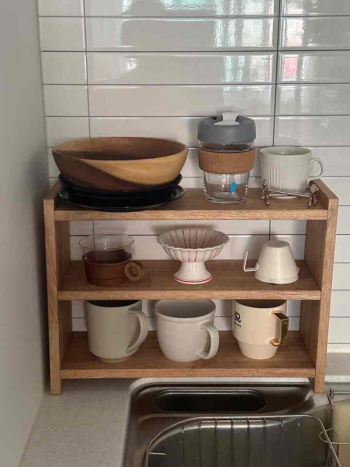 ナチュラルな木目調のキッチン棚にボウルとカップが整然と並んだ清潔感のあるキッチンスペース