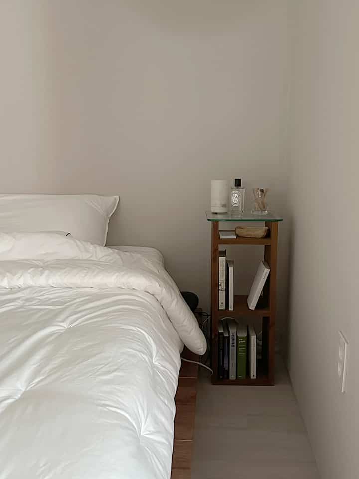 白と木目調の調和がとれた寝室、シンプルなベッドとナイトテーブルが落ち着いた雰囲気を作るインテリア