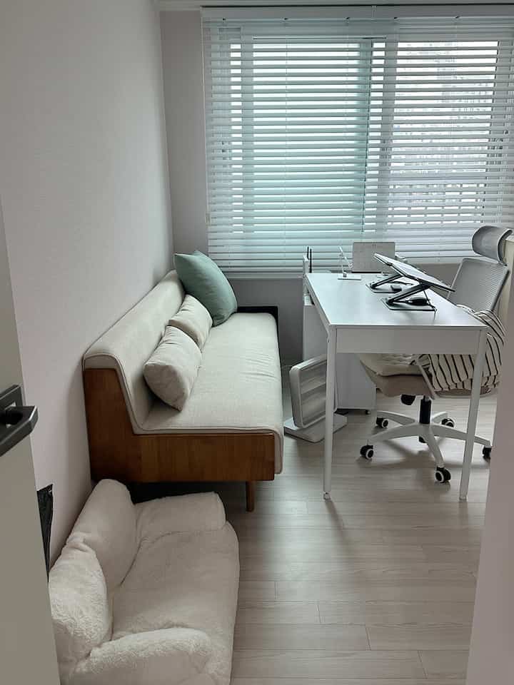 ホワイトと木目調のコンパクトなホームオフィス、ベージュのソファとオフィスチェアが配置された雰囲気のあるインテリア