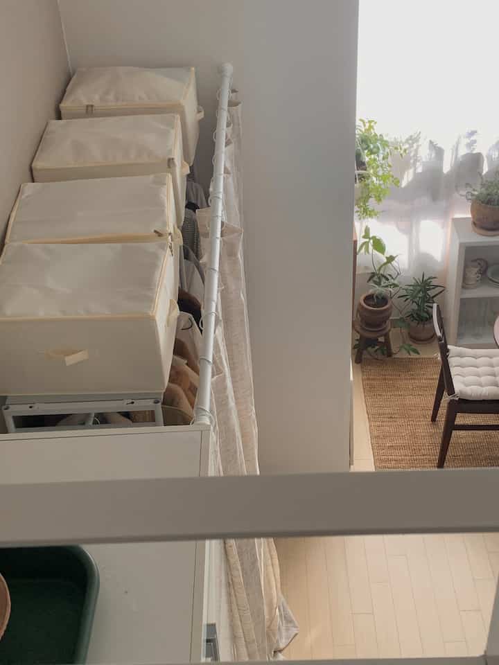 ナチュラルカラーのワンルームのクローゼット横に、カーテンとリビングボックス付きのハンガーラックが配置された整った収納スペース