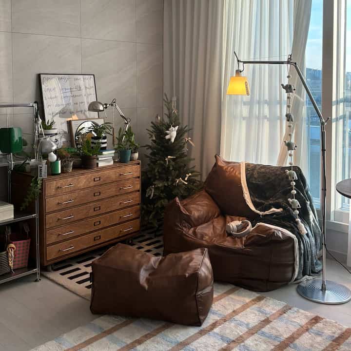 ナチュラルカラーのリビング、ブラウンのビーズクッションとクリスマスツリー、フロアランプが配置された温かみのある空間