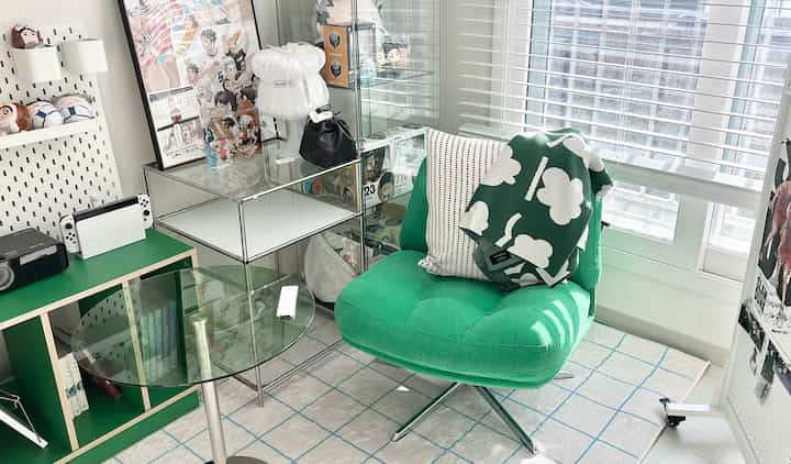 明るい色調のワンルームリビング、緑のアームチェアとガラスのサイドテーブルが配置されたモダンでコンパクトなインテリア