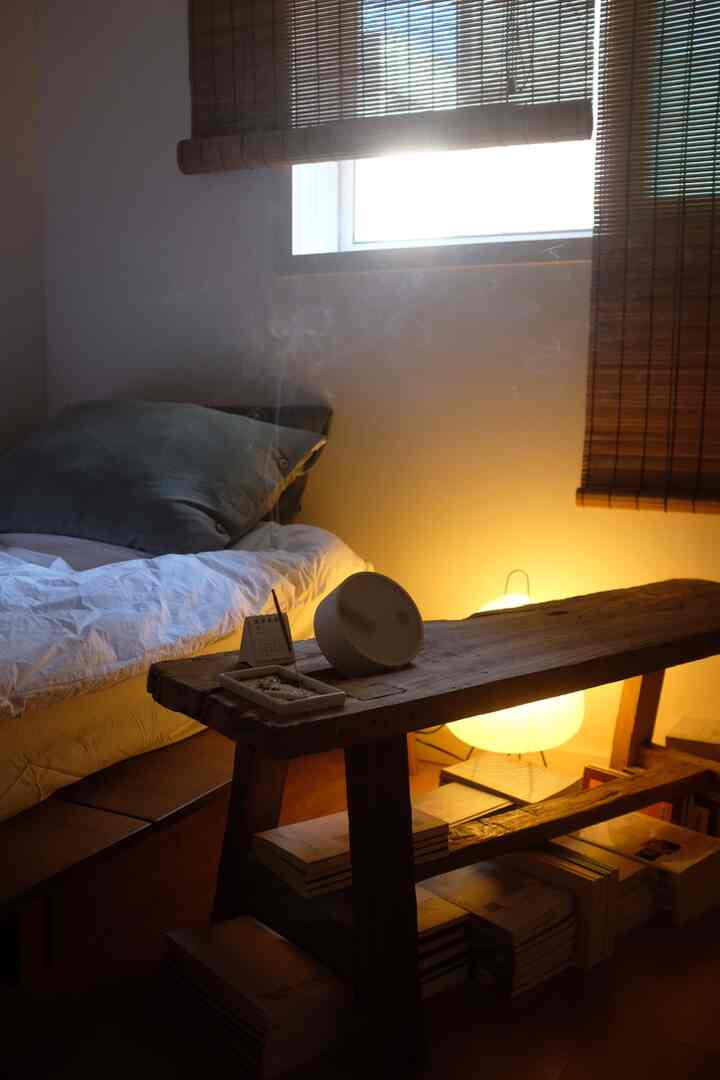 暖かいナチュラルカラーの木製ベンチが配置された居心地の良い寝室。低い天井と狭い部屋の特徴が際立つインテリア