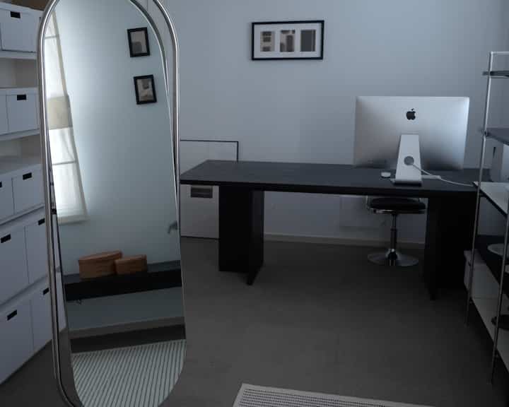 黒と白のミニマルなホームオフィス、パソコンデスクとオフィスチェア、整頓された棚が配置された落ち着いた作業空間