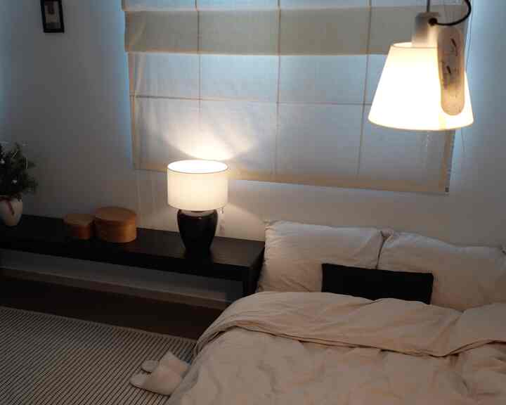 ベージュ調の寝室、ベッドとナイトテーブル、ラグが配置された落ち着いた空間