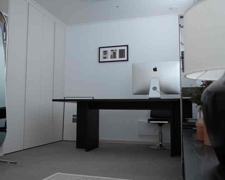 白と黒のトーンのホームオフィス、黒い机とオフィスチェアが配置され、清潔感とモダンな雰囲気のある部屋