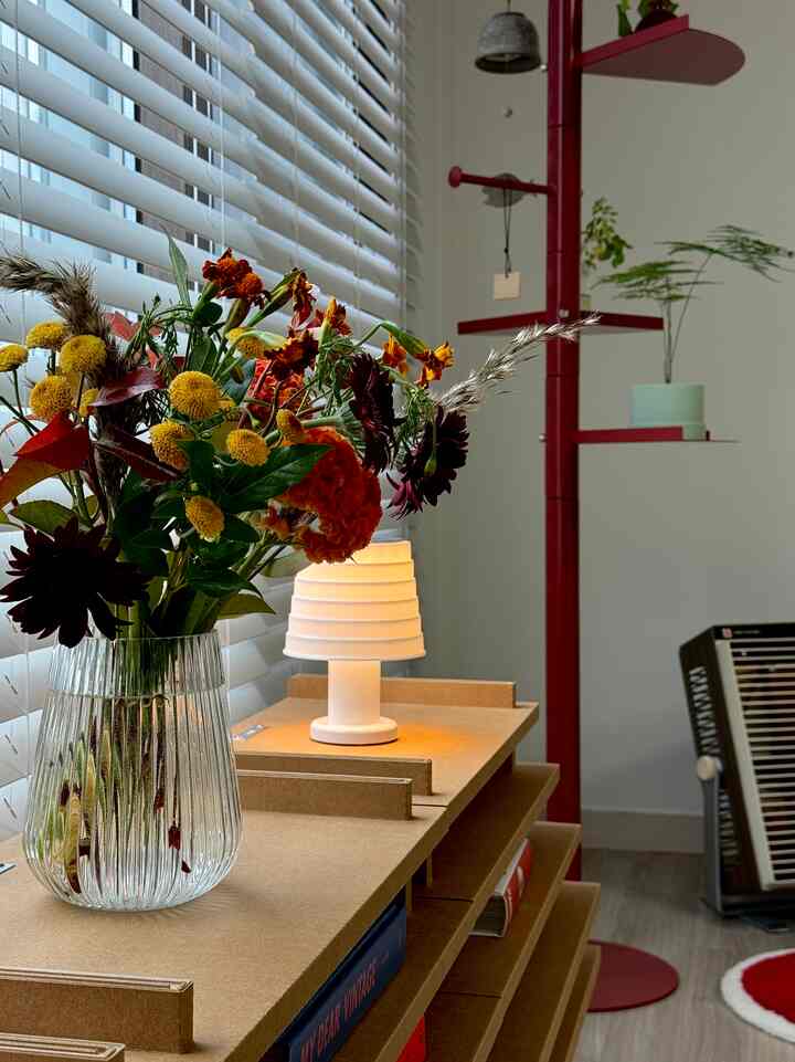 赤とベージュの色調のリビング、ブラインドや花瓶、暖かい照明が配置された雰囲気あるインテリア