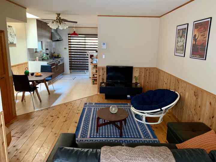 白と木目調のリビングとキッチン、ブルーのラグとペンダントライトが印象的なシンプルなインテリア