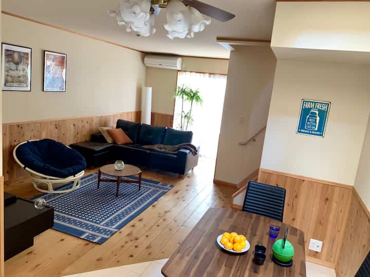 ネイビーブルーのソファと木目調の床、ラグが配置された居心地の良いリビング