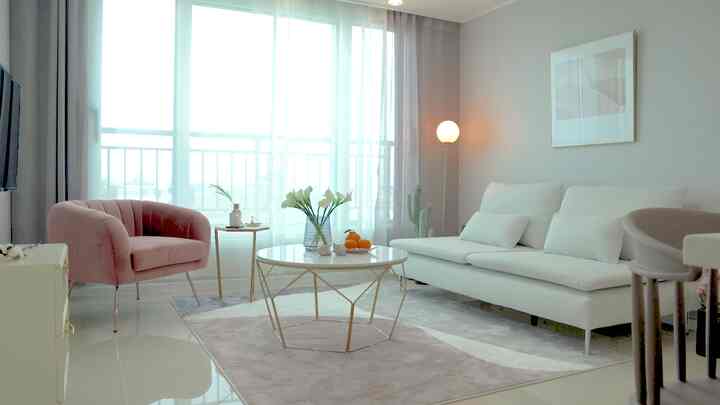White and pink toned living room featuring a modern sofa, coffee table, and a floor lamp creating a cozy atmosphere