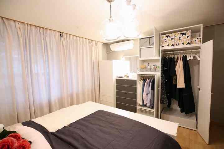 A white and dark gray toned bedroom featuring a bed and closet arranged neatly in a minimal storage space