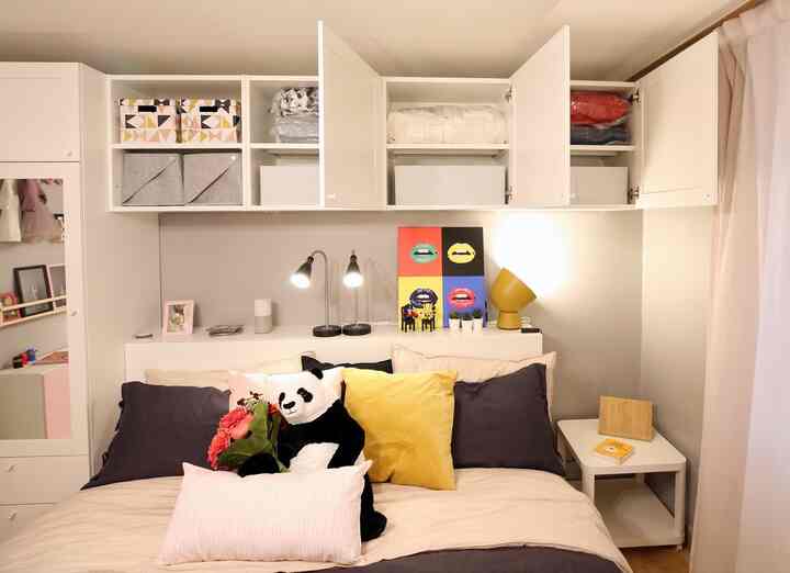 A cozy 6-tatami bedroom in white and dark gray tones, featuring assorted cushions and colorful wall art above the bed