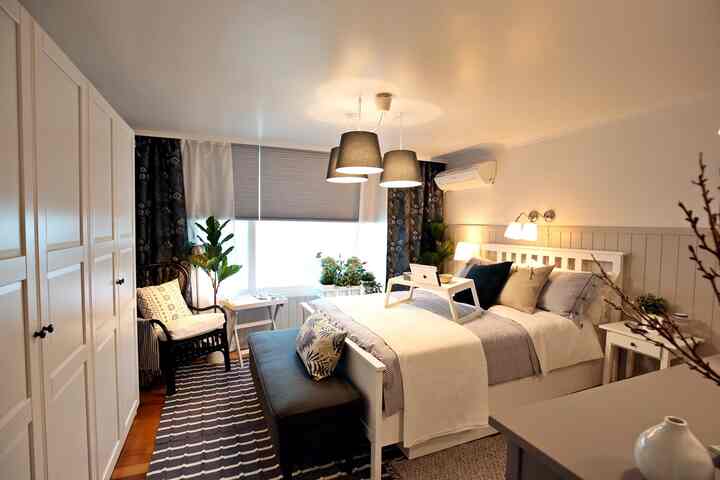 White and black toned bedroom with plants near window, creating a natural and cozy atmosphere