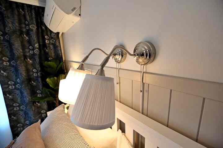 A bedroom with white walls and headboard featuring wall sconces, creating a cozy atmosphere