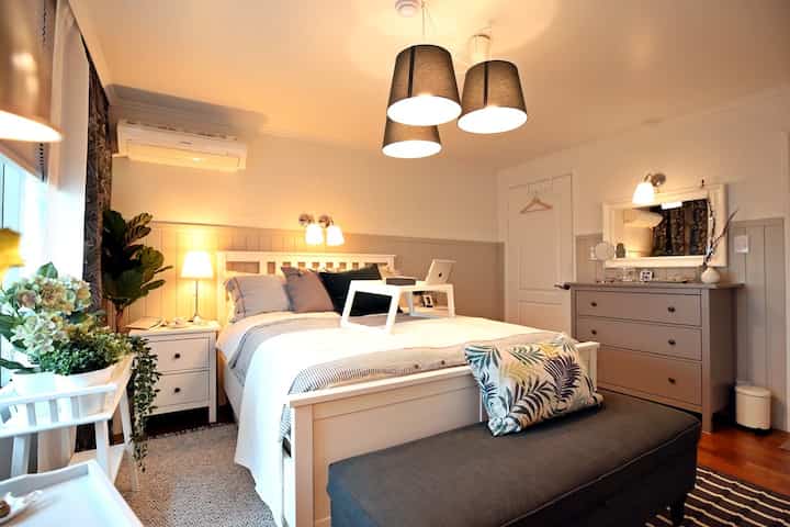 A white and gray toned bedroom featuring a bed, nightstand, and dresser arranged in a simple modern style