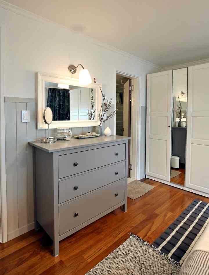 白とグレーの木目調が調和した寝室、チェストとクローゼットが配置され整理された印象的なインテリア