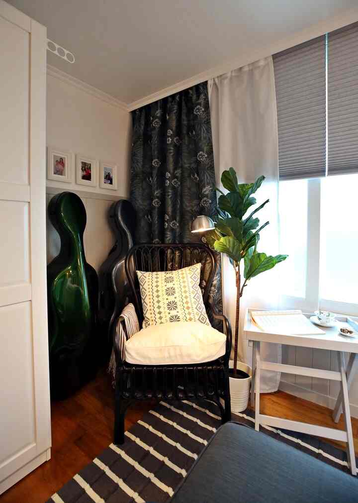 白と黒の調和が取れた狭いリビングの読書コーナー、ラタンのアームチェアと室内植物が配置された雰囲気のある空間