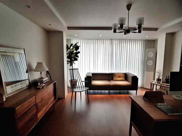 A natural modern living room with white and wood tones, featuring a centrally placed modern sofa and armchair