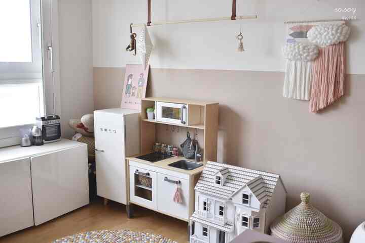 ベージュとナチュラルな木目調の子供部屋、スメールグの木製キッチン玩具と家族のポスターが配置された雰囲気のある空間