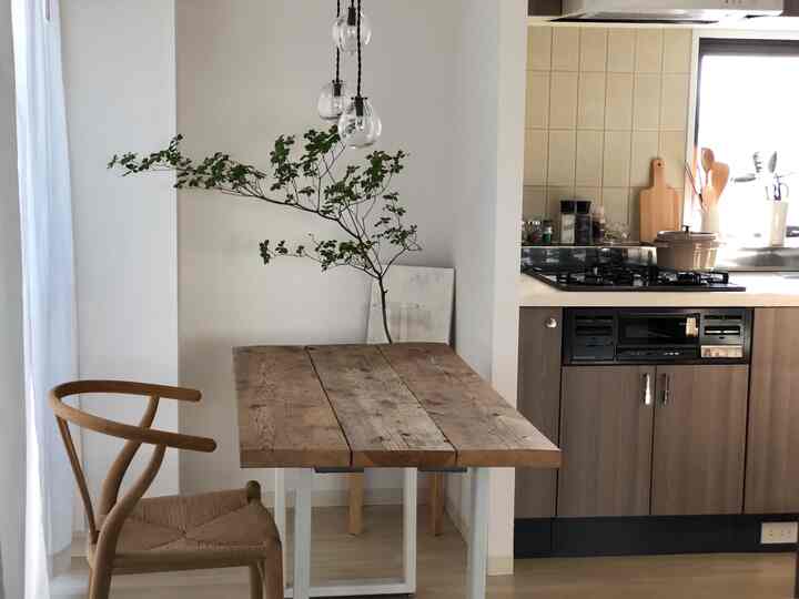 白を基調としたキッチン兼ダイニング、ヴィンテージの木製ダイニングテーブルとYチェアが配置されたシンプルで自然な雰囲気の空間