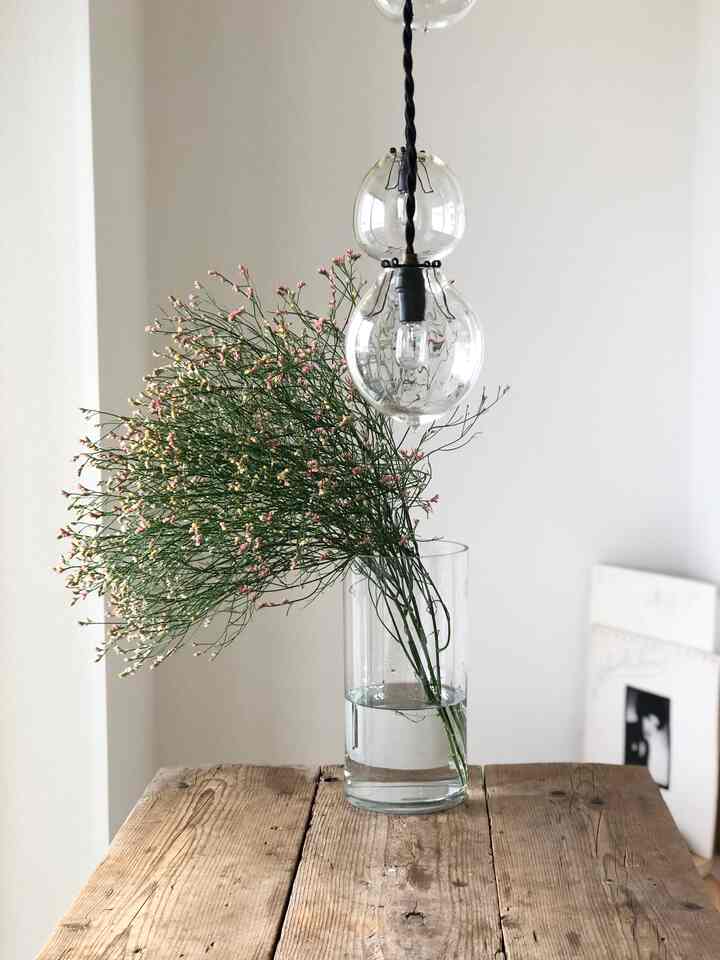 ナチュラルな木目調のダイニングテーブルと透明なガラスの花瓶が配置されたシンプルなキッチン空間