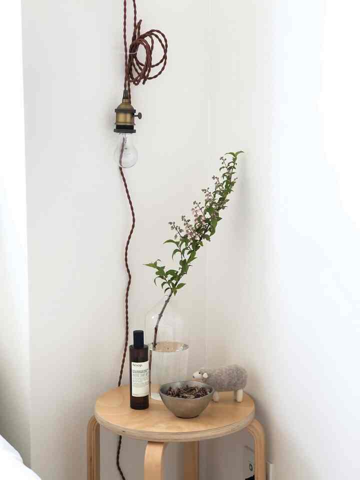 白と木目調の寝室サイドテーブルコーナー、シンプルな小物と自然な雰囲気のあるインテリア