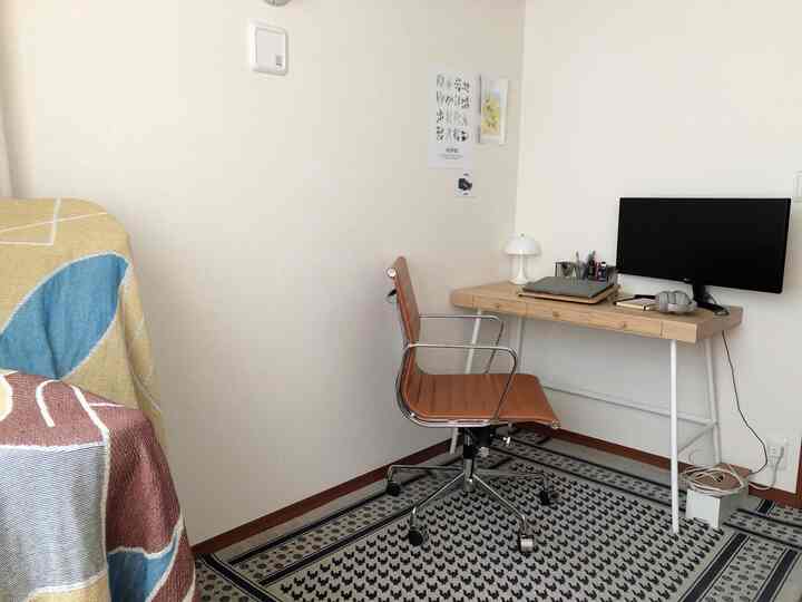 白と木目調が調和するコンパクトなホームオフィス、机の上にモニターと照明が整然と配置された実用的な空間