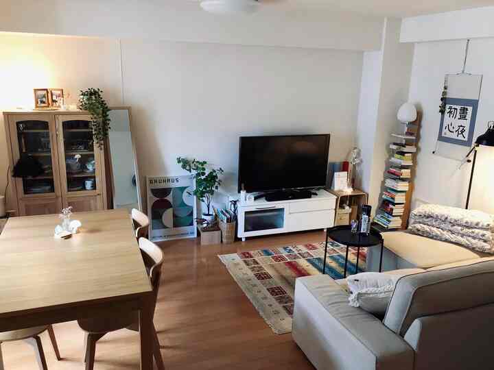 明るい木目調と白色が調和したリビング、木製ダイニングテーブルとアイボリーのソファが配置された落ち着いた空間