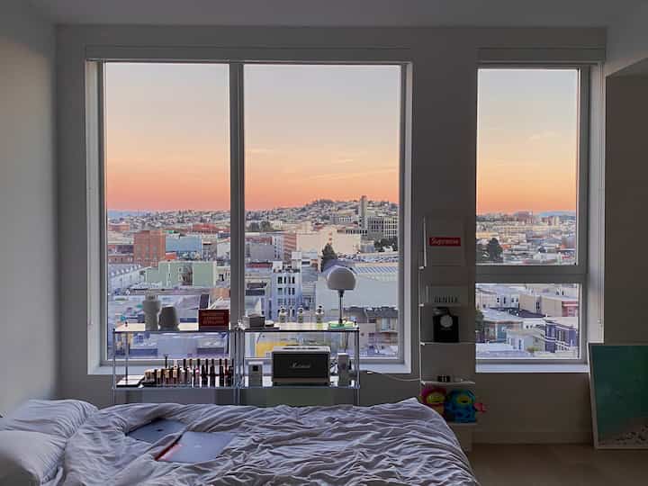 夕焼けが美しい大きな窓のあるホワイト寝室、整ったベッドとミニマルなインテリアが印象的な空間