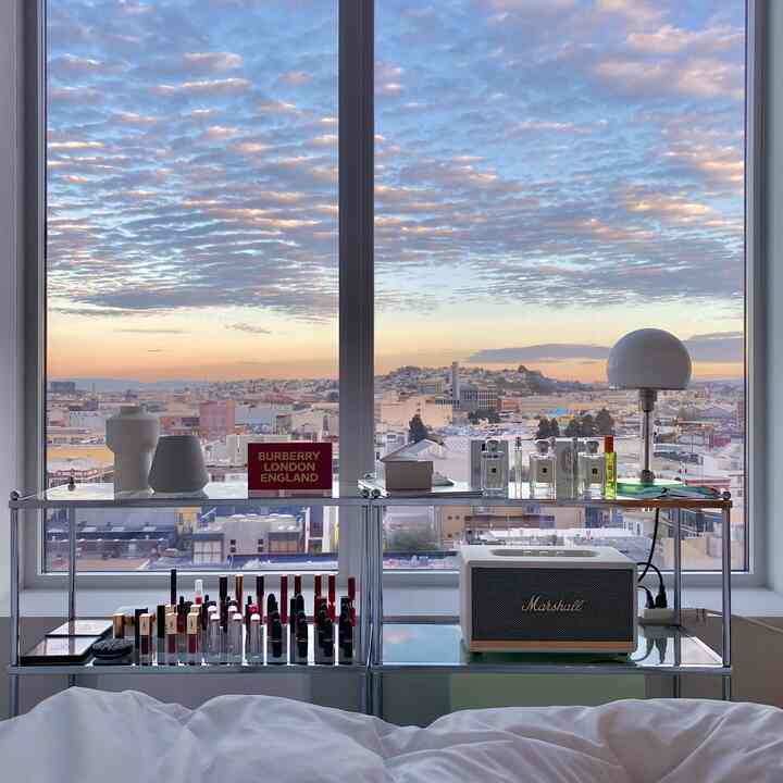 空色と白のトーンの寝室、メタルシェルフに照明とオブジェが配置された清潔でモダンなインテリア