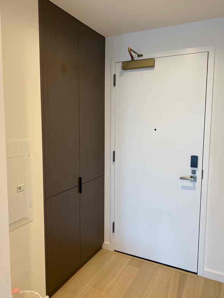 ナチュラルトーンの床と白いドア、濃い茶色のシューズラックが配置されたすっきりとした玄関スペース