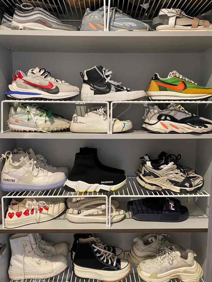 白を基調としたシューズラック、高さの異なる棚に様々なスニーカーやサンダルが整理された雰囲気のある空間