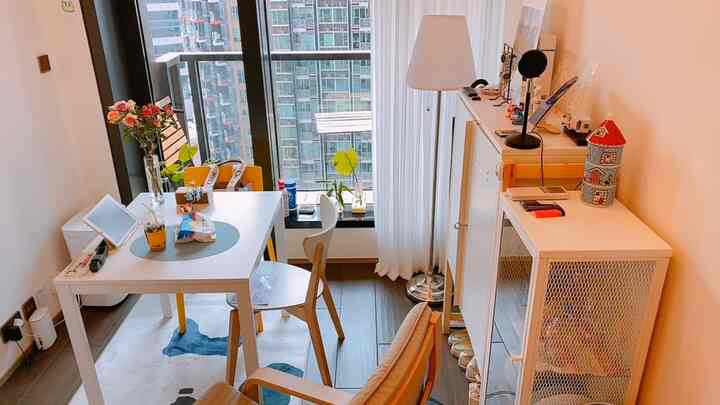 明るいホワイトと木目調が調和する狭いダイニングスペース、食卓と椅子、収納キャビネットが配置されたコンパクトなワンルーム