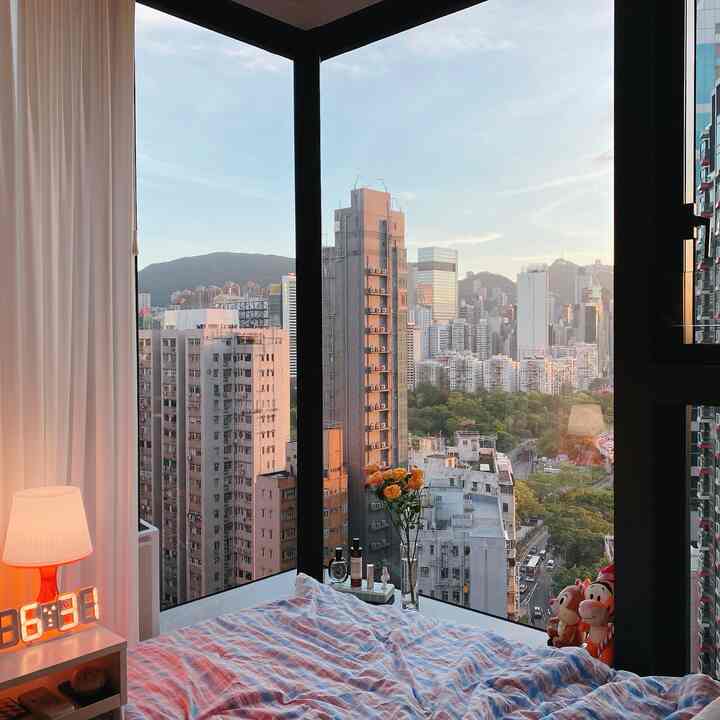 白いカーテンとベッドが配置された寝室、大きな窓から都市の景色が見える雰囲気のあるインテリア