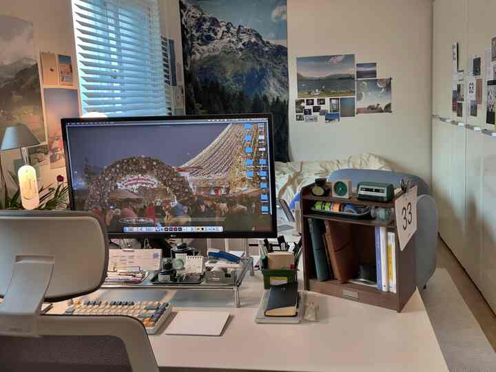 ホワイトとブラウンのトーンのホームオフィス、大きなモニターと整理されたデスク、ポスターと壁飾りが調和した居心地の良い作業空間