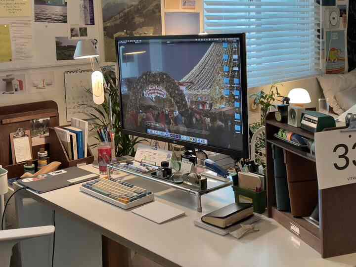 ホワイトとウッドトーンの調和したホームオフィス空間、大型モニターと整理されたデスク用品が配置された印象的なデスクインテリア。