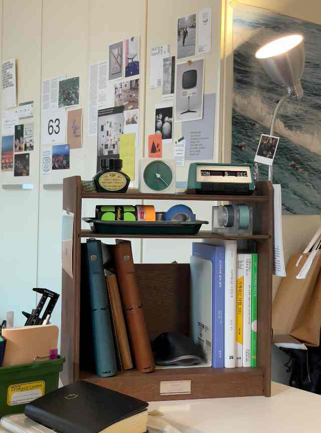 ブラウンの木目調デスクと棚が置かれたホームオフィス空間、多彩な文具と整理用品が整頓された雰囲気のあるインテリア