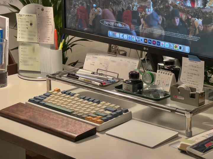 ホワイトとステンレスの木目調が調和するデスクトップホームオフィス、モニタースタンドとトレイで整頓されたワークスペース