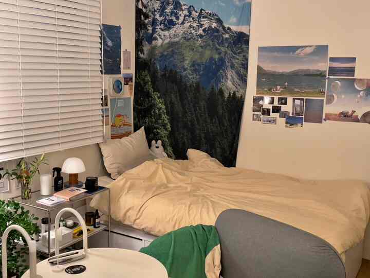 ベージュとアイボリー調の寝室、大きなファブリックポスターと収納付きベッドフレームが配置された居心地の良いインテリア