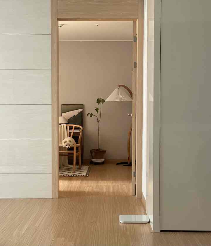 ベージュと木目調の寝室、快適なアームチェアとフロアランプ、植物が配置された自然で落ち着いた雰囲気のインテリア