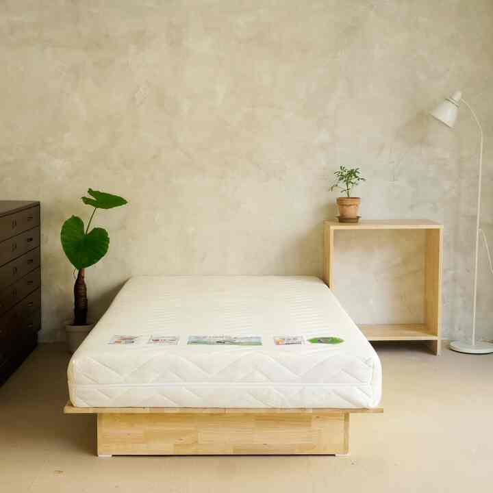 ナチュラルトーンの寝室、平床とナイトテーブルが配置されたミニマルで落ち着いた雰囲気のインテリア